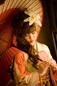 和傘を持って手元を見つめる振袖を着た二十歳