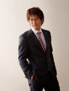 スーツを着た成人男性がポケットに手を入れ横を向いている