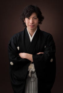 羽織袴を着た成人男性が腕組みをして正面を向いている