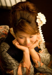 和室で頬杖をついた振袖を着た二十歳の女性