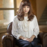 微笑みながら椅子に座った二十歳の女性