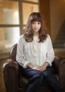 微笑みながら椅子に座った二十歳の女性