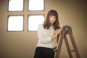 脚立に肘をかけ見つめる女性