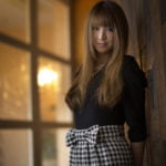 両手を後ろに組んで微笑む女性