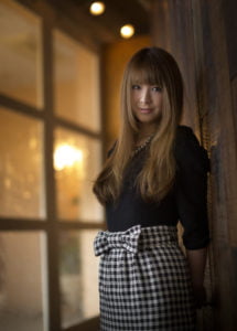 両手を後ろに組んで微笑む女性