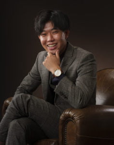 スーツを着た成人男性が座って頬杖をついている