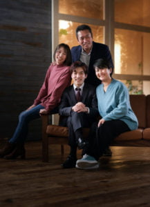 椅子に座ったスーツ男性を囲んだ家族