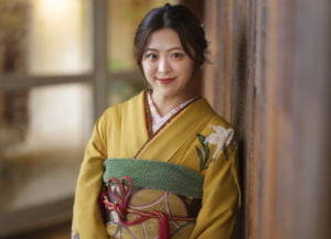 壁に寄り掛かる振袖を着た女性