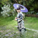 振袖を着た成人女性が和傘を持って立っている