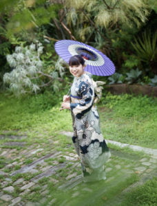 振袖を着た成人女性が和傘を持って立っている