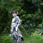 バックを両手に持って立つ振袖を着た成人女性