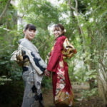 手を繋ぎ振り向く振袖を着た成人女性2人