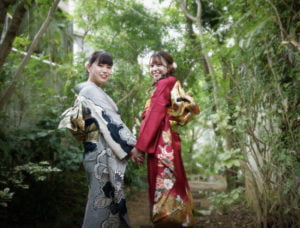 手を繋ぎ振り向く振袖を着た成人女性2人