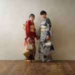 振袖を着た成人女性2人が手を繋いで立っている